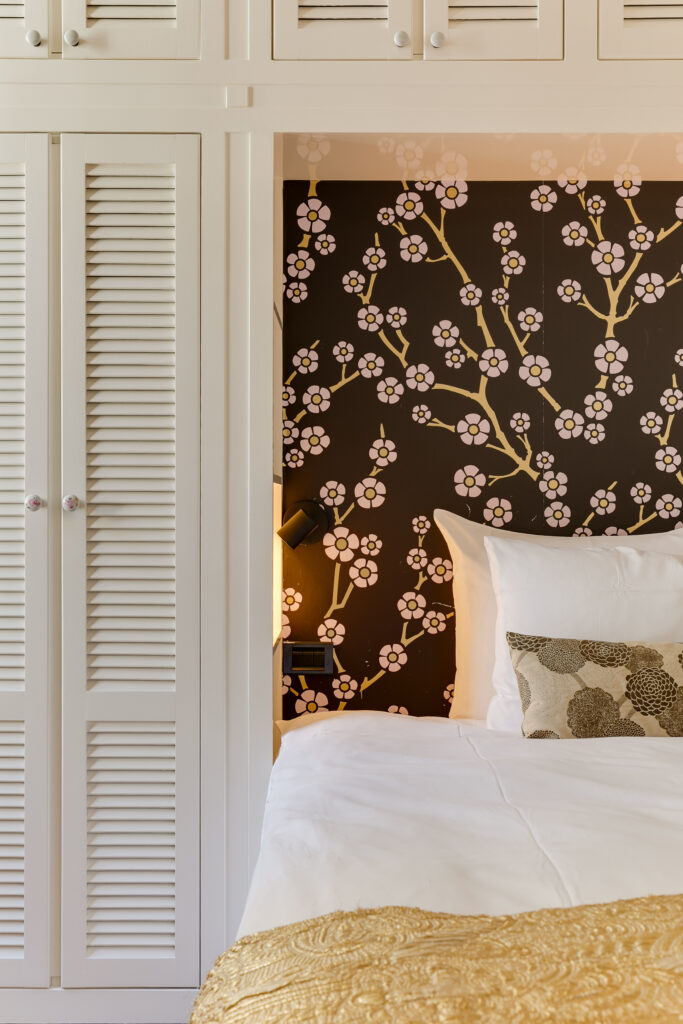 Habitación de hotel boutique con papel pintado de flores y acogedora ropa de cama en Amberes
